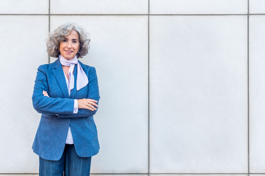 A woman in a blue blazer standing outdoors, confident