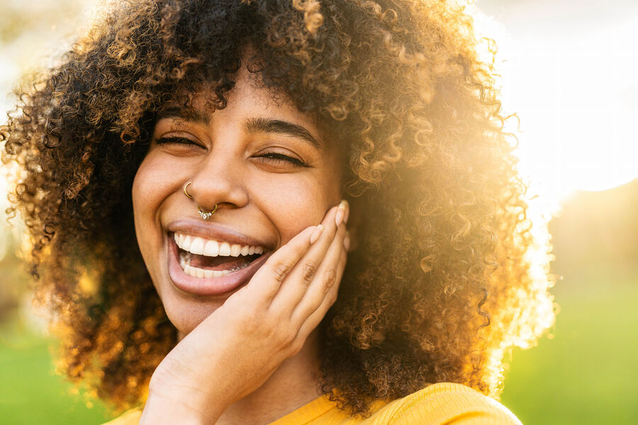 A woman in sunshine, eyes closed, gentle smile